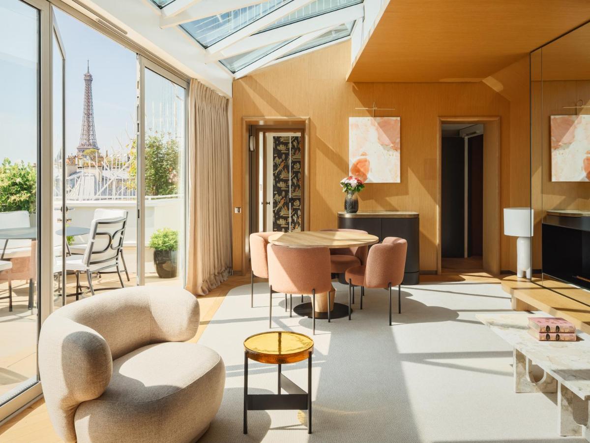 un salon avec une table et des chaises et la tour Eiffel dans l'établissement Hôtel De Sers Champs Elysées Paris, à Paris