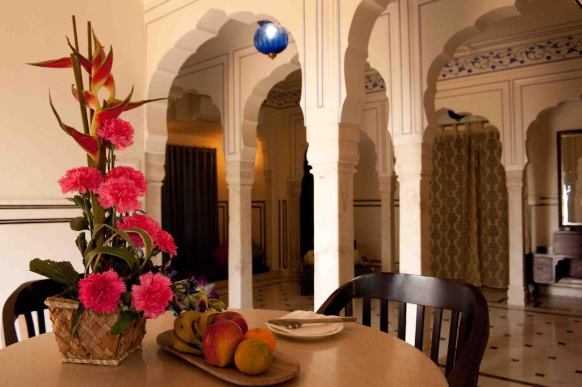 a table with a vase of flowers and fruit on it at Royal Heritage Haveli - By Leisure Hotels in Jaipur