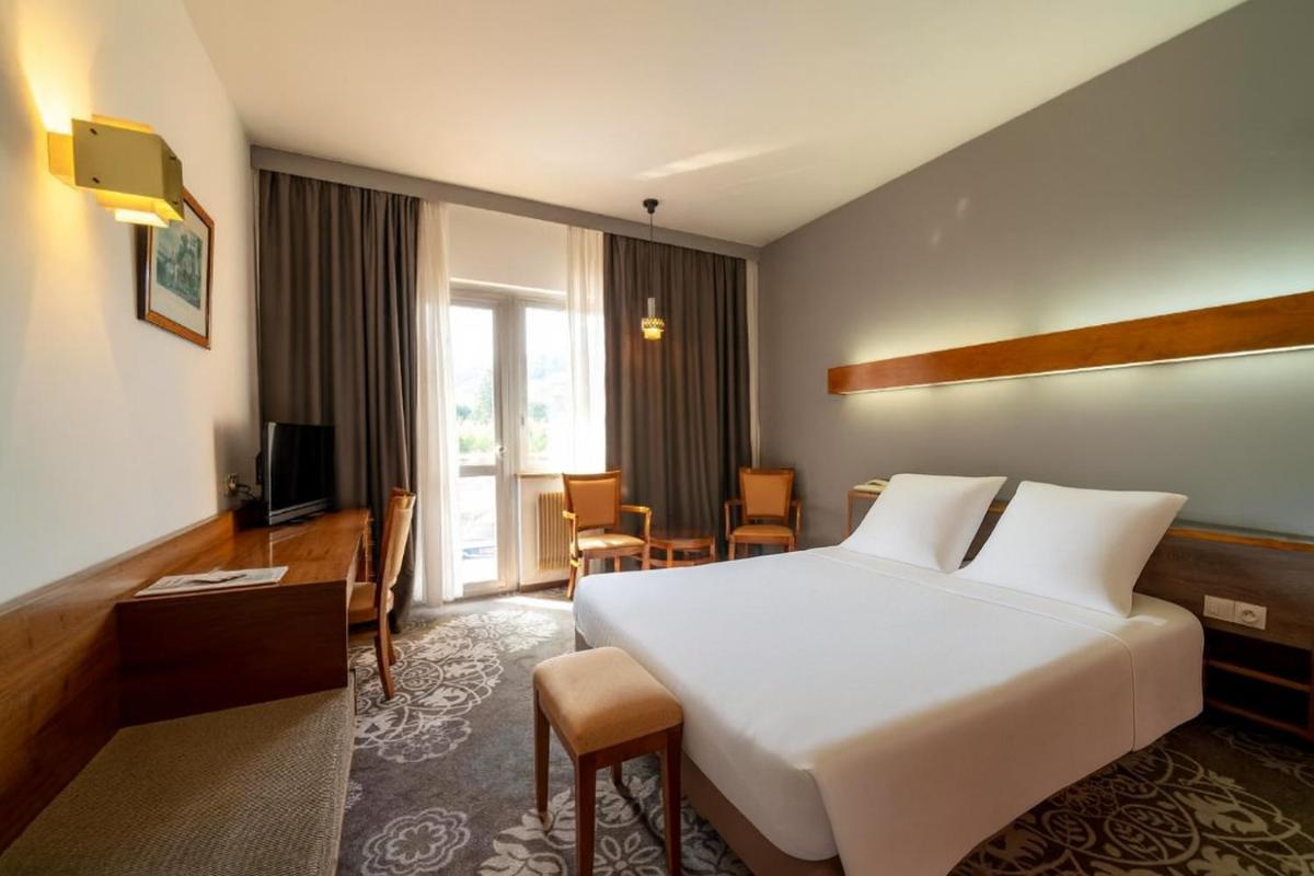 une chambre d'hôtel avec un grand lit et un bureau dans l'établissement Hotel Munsch Restaurant & Wellness, Colmar Nord - Haut-Koenigsbourg, à Saint-Hippolyte