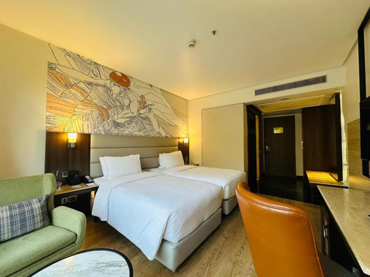 a hotel room with two beds and a couch at Hyatt Centric Rajpur Road Dehradun in Dehradun