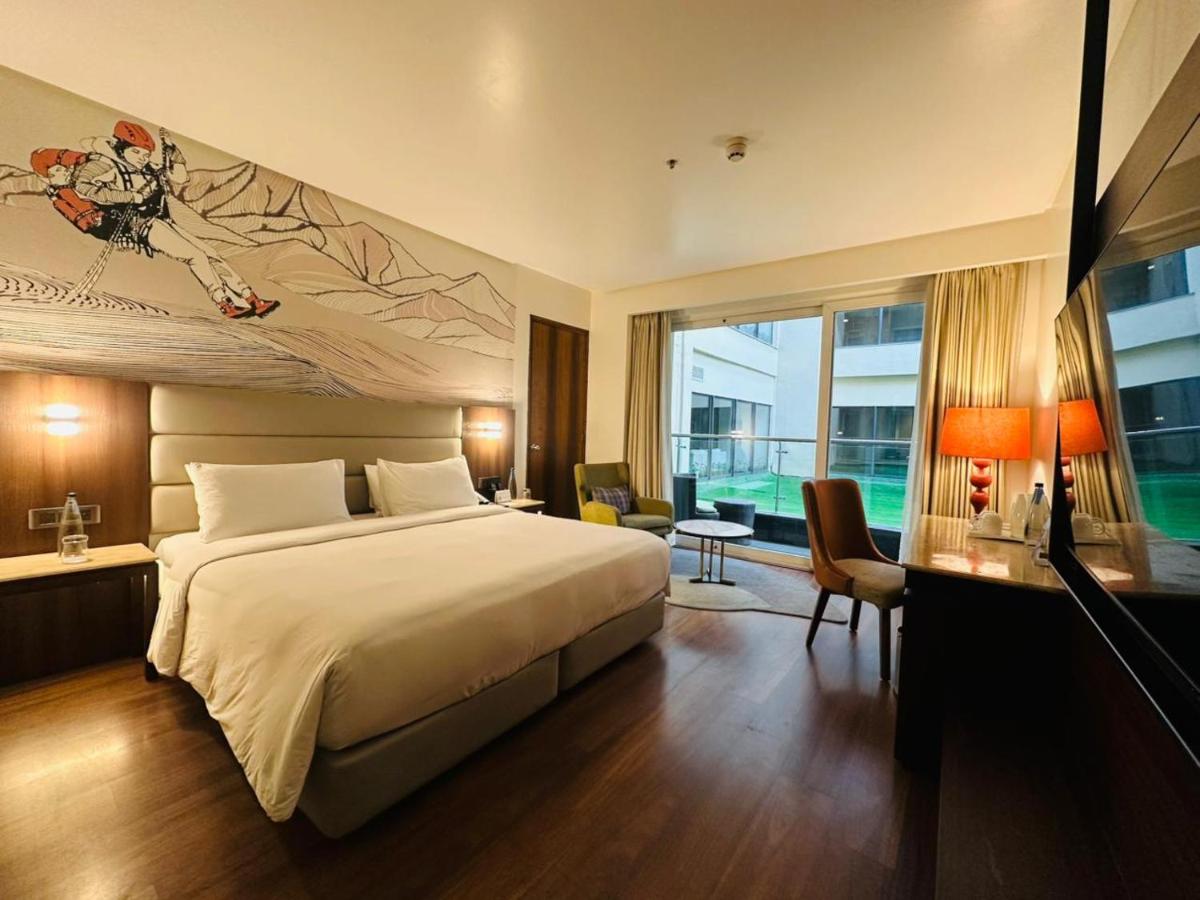 a hotel room with a bed and a large window at Hyatt Centric Rajpur Road Dehradun in Dehradun