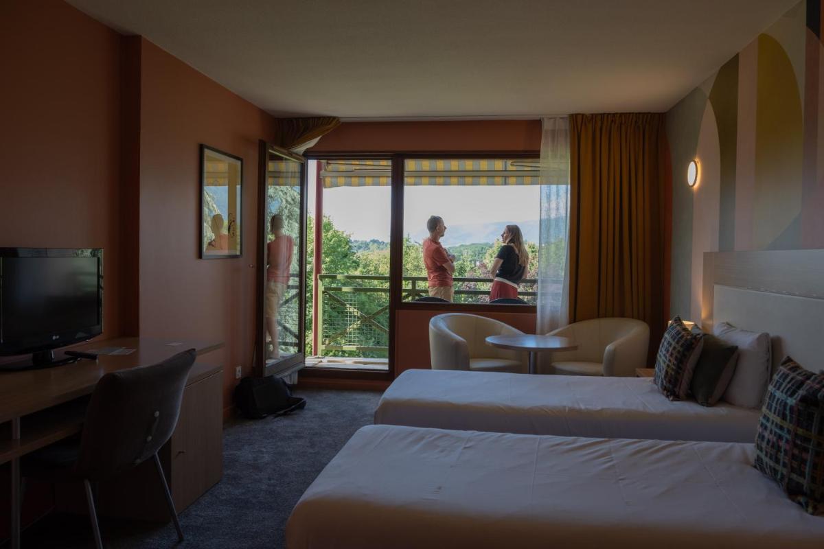 une chambre d'hôtel avec deux lits et un balcon dans l'établissement Hotel *** & Spa Vacances Bleues Villa Marlioz, à Aix-les-Bains