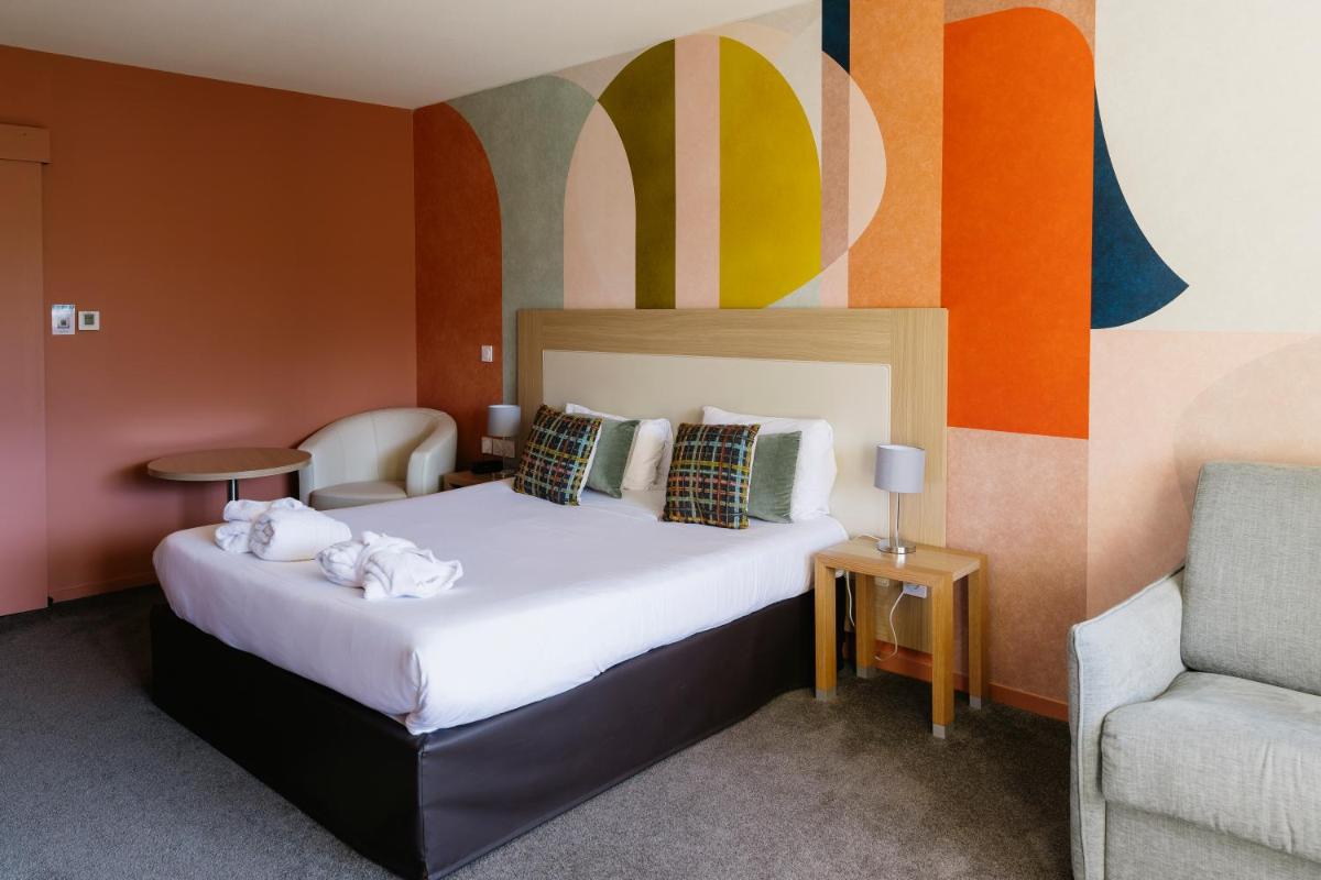 une chambre d'hôtel avec un lit et une chaise dans l'établissement Hotel *** & Spa Vacances Bleues Villa Marlioz, à Aix-les-Bains