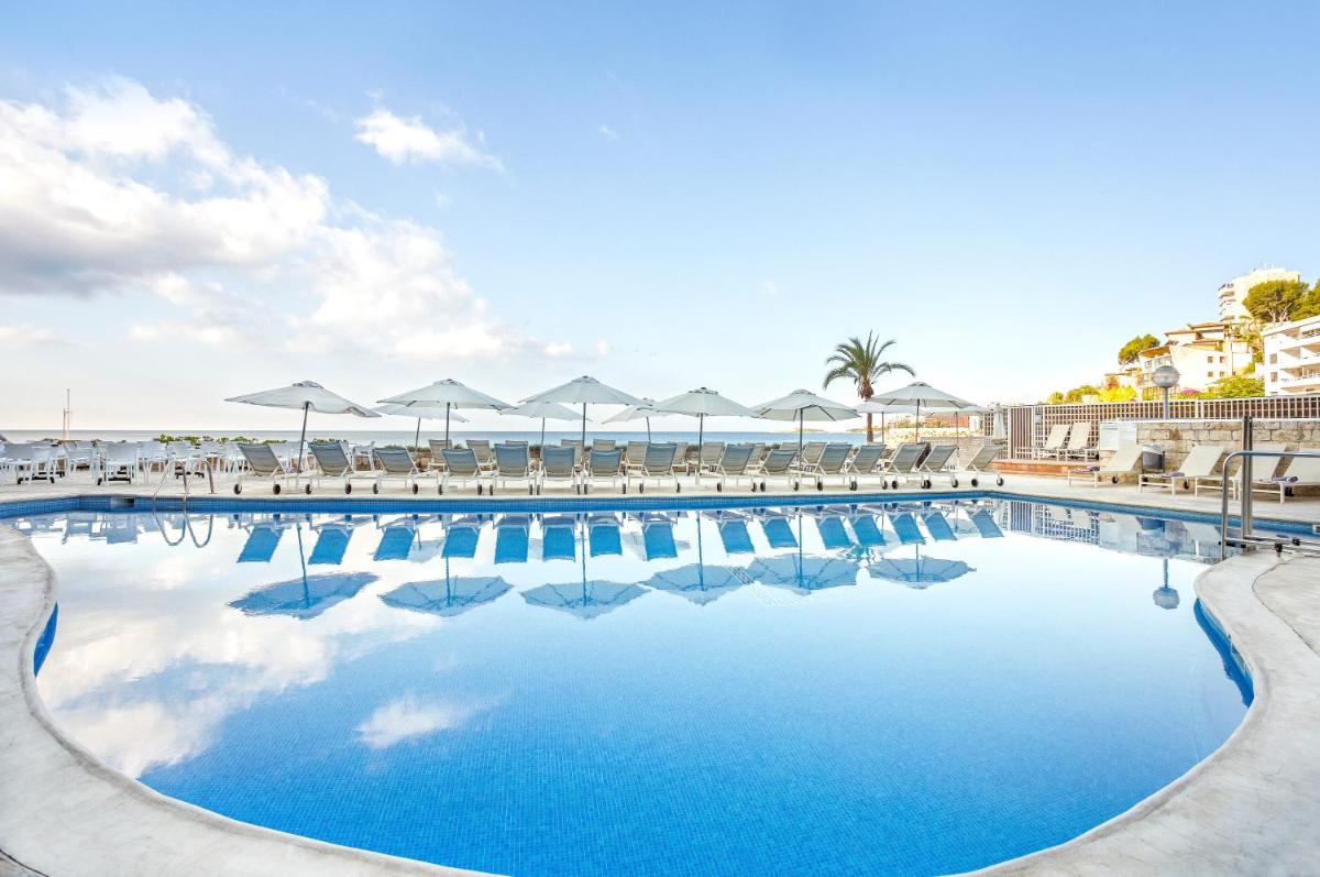 una gran piscina con sillas y sombrillas en Hotel Be Live Adults Only Marivent, en Palma de Mallorca