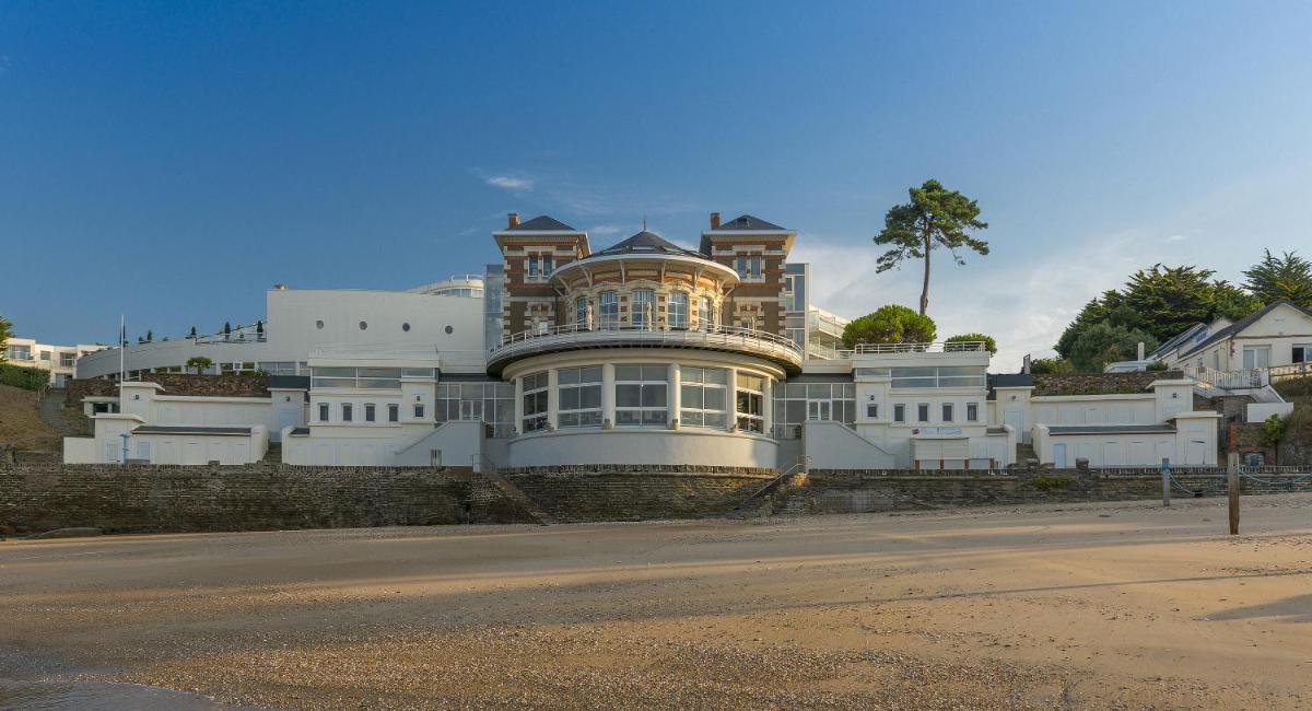 une grande maison blanche sur le côté d'une rue dans l'établissement Alliance Pornic Hôtel Thalasso & Spa, à Pornic