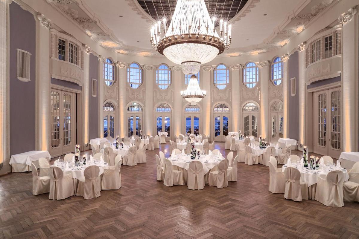ein Ballsaal mit weißen Tischen und Stühlen und einem Kronleuchter in der Unterkunft ATLANTIC Grand Hotel Travemünde in Travemünde