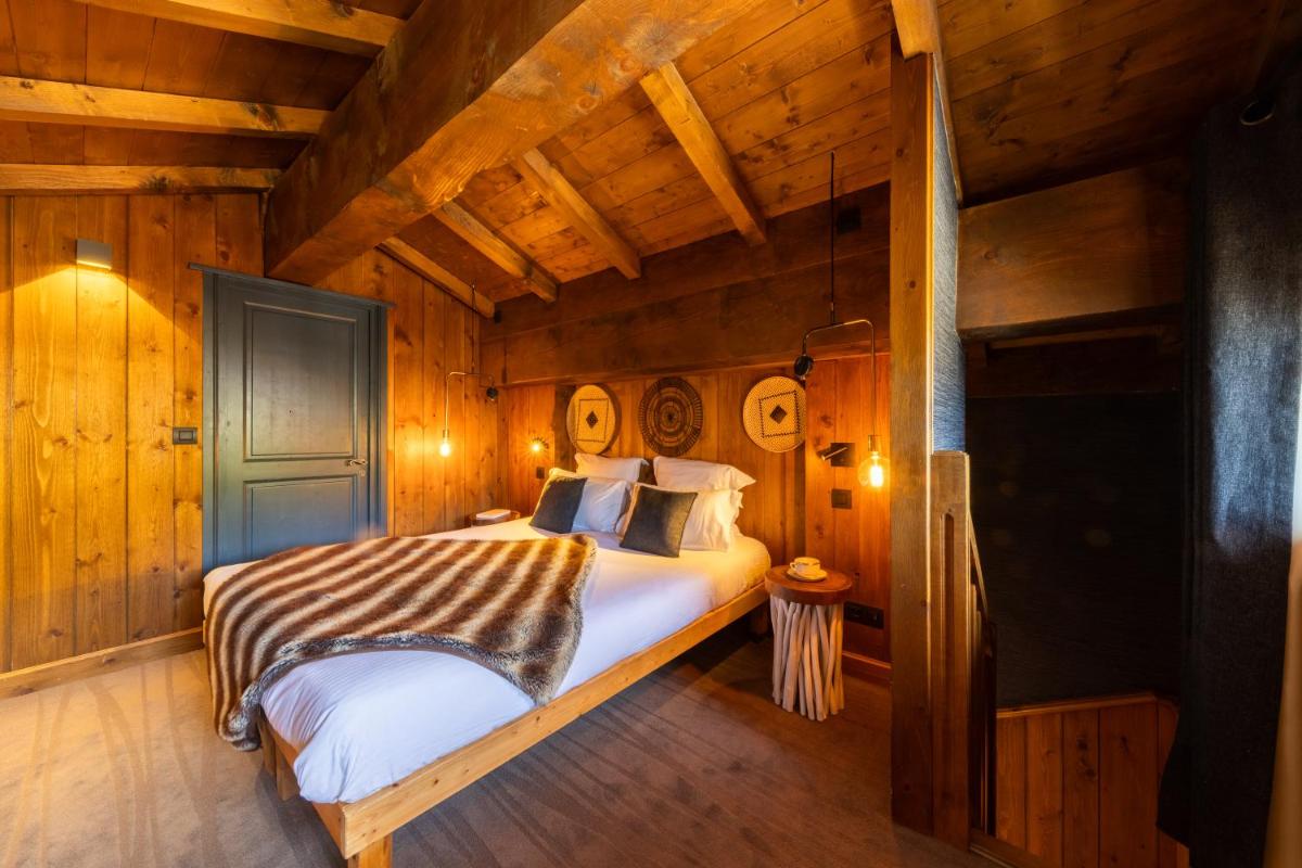 une chambre avec un lit dans une pièce aux murs en bois dans l'établissement Hôtel Village Montana by Les Etincelles, à Tignes