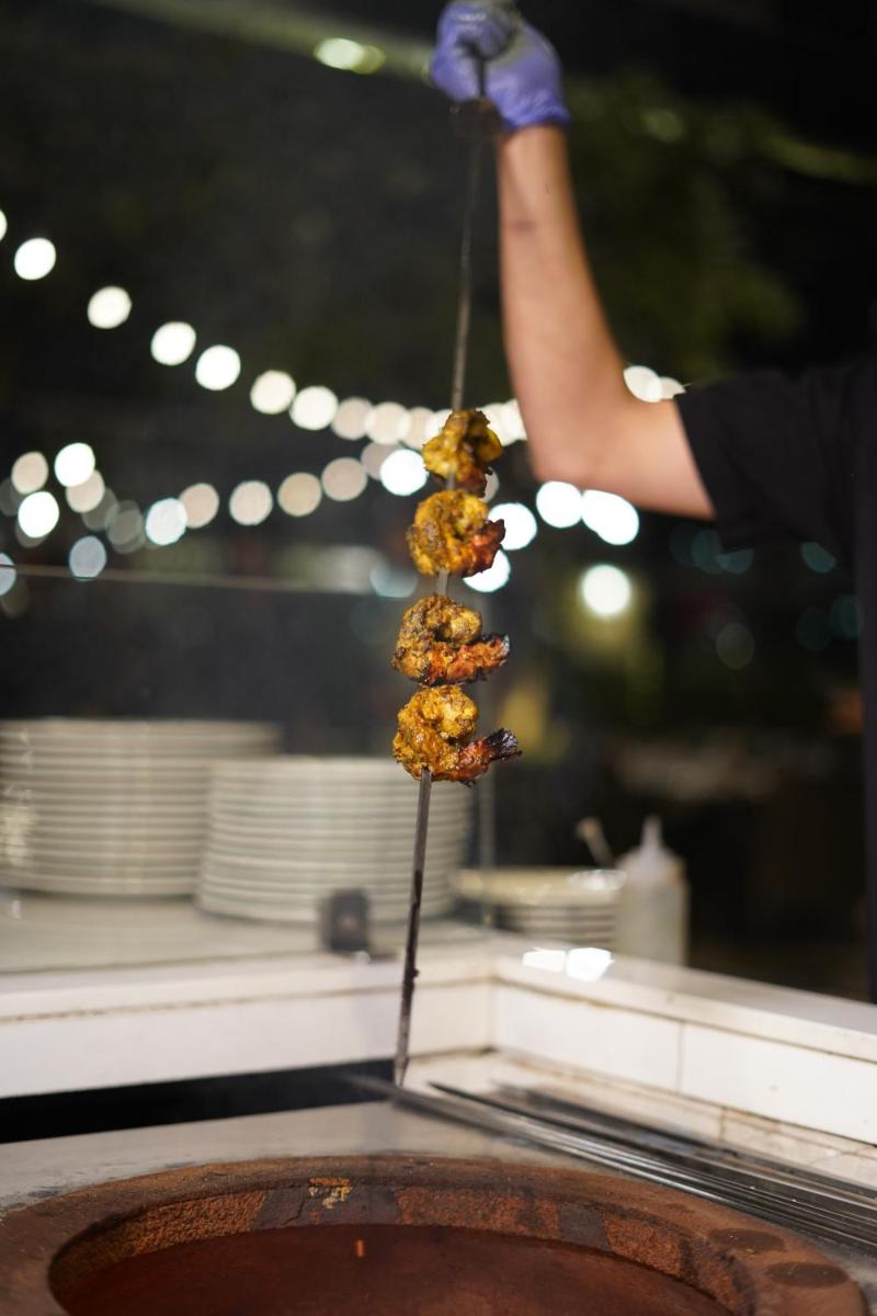 a person holding a stick with food on it at Courtyard by Marriott Gurugram Downtown in Gurgaon