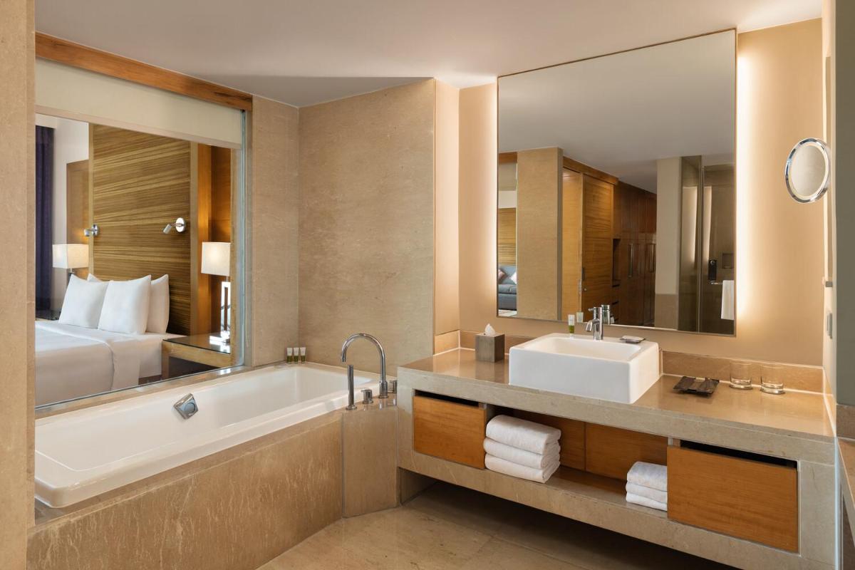 a bathroom with a tub and a sink and a bed at Courtyard by Marriott Gurugram Downtown in Gurgaon
