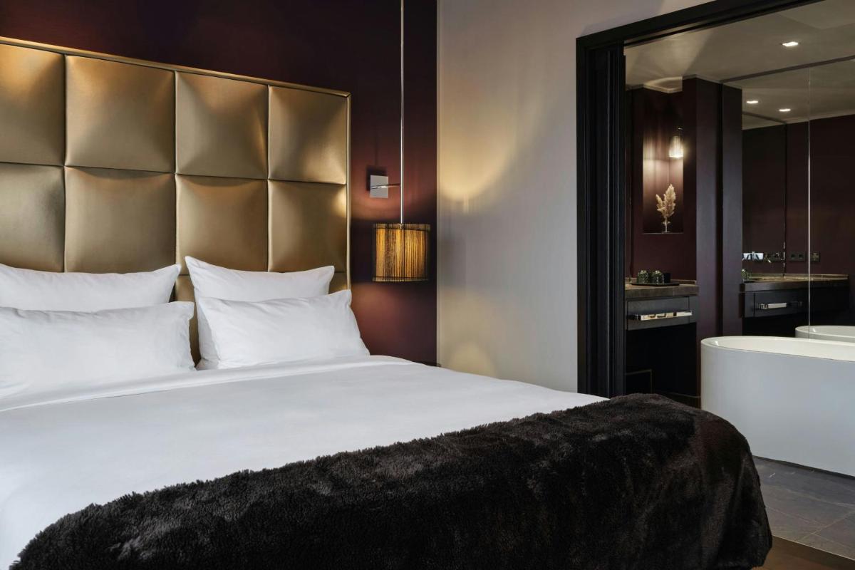 ein Schlafzimmer mit einem großen weißen Bett und ein Badezimmer in der Unterkunft Roomers Frankfurt Central, Autograph Collection in Frankfurt am Main