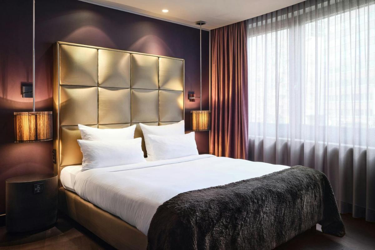 ein Schlafzimmer mit einem großen Bett und einem großen Fenster in der Unterkunft Roomers Frankfurt Central, Autograph Collection in Frankfurt am Main