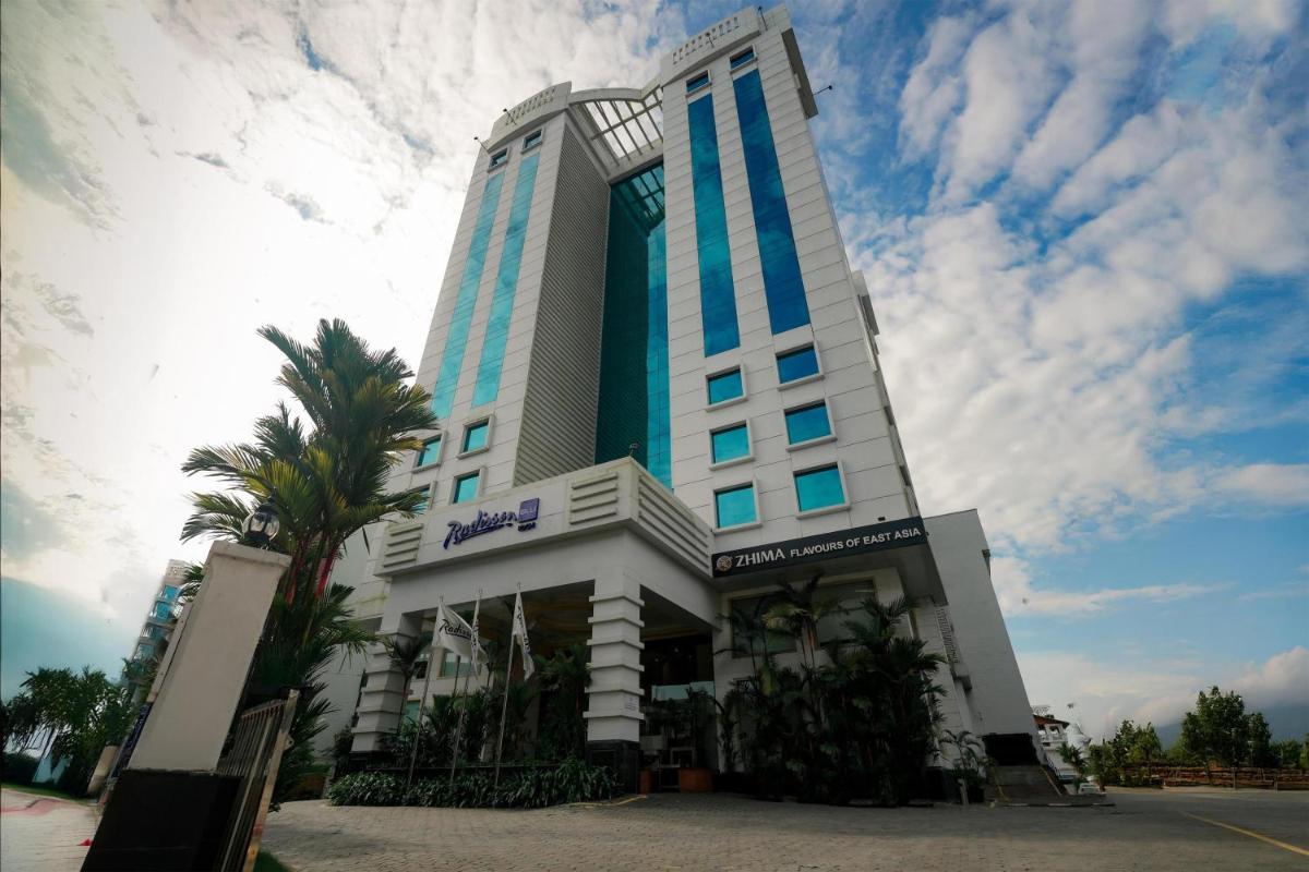 a large building with a palm tree in front of it at Radisson Blu Kochi in Cochin