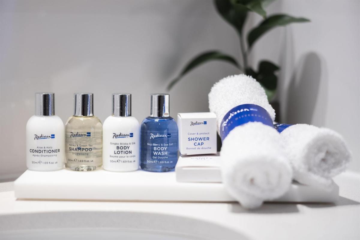 a bathroom counter with several bottles of soap and a stuffed animal at Radisson Blu Kochi in Cochin