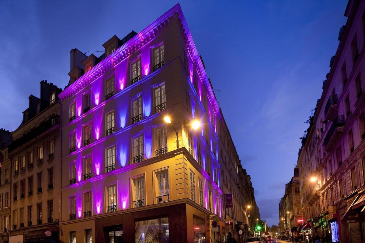 un bâtiment avec des lumières violettes sur le côté dans l'établissement Secret de Paris - Hotel & Spa, à Paris
