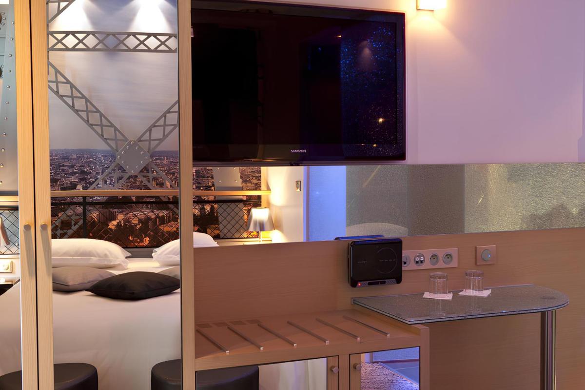 une chambre avec un lit et une grande télévision au mur dans l'établissement Secret de Paris - Hotel & Spa, à Paris