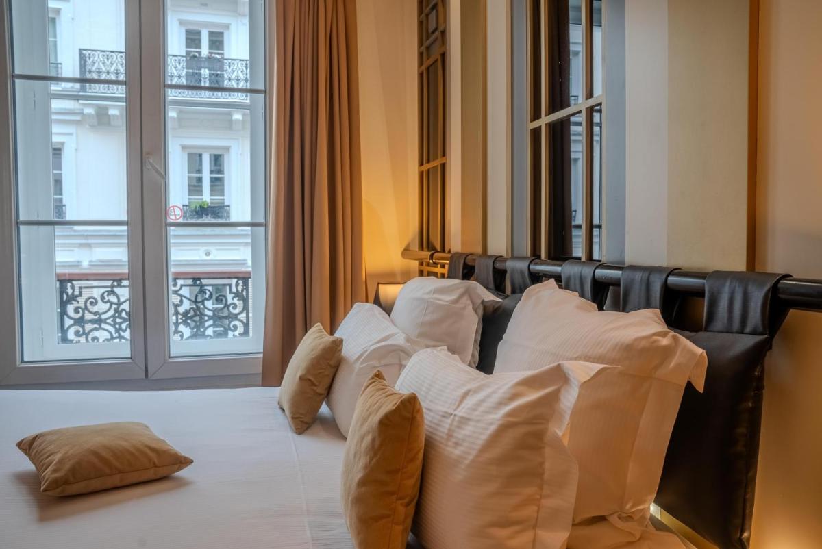 un lit avec des oreillers blancs dans une chambre avec une fenêtre dans l'établissement Secret de Paris - Hotel & Spa, à Paris 75 autres photos
