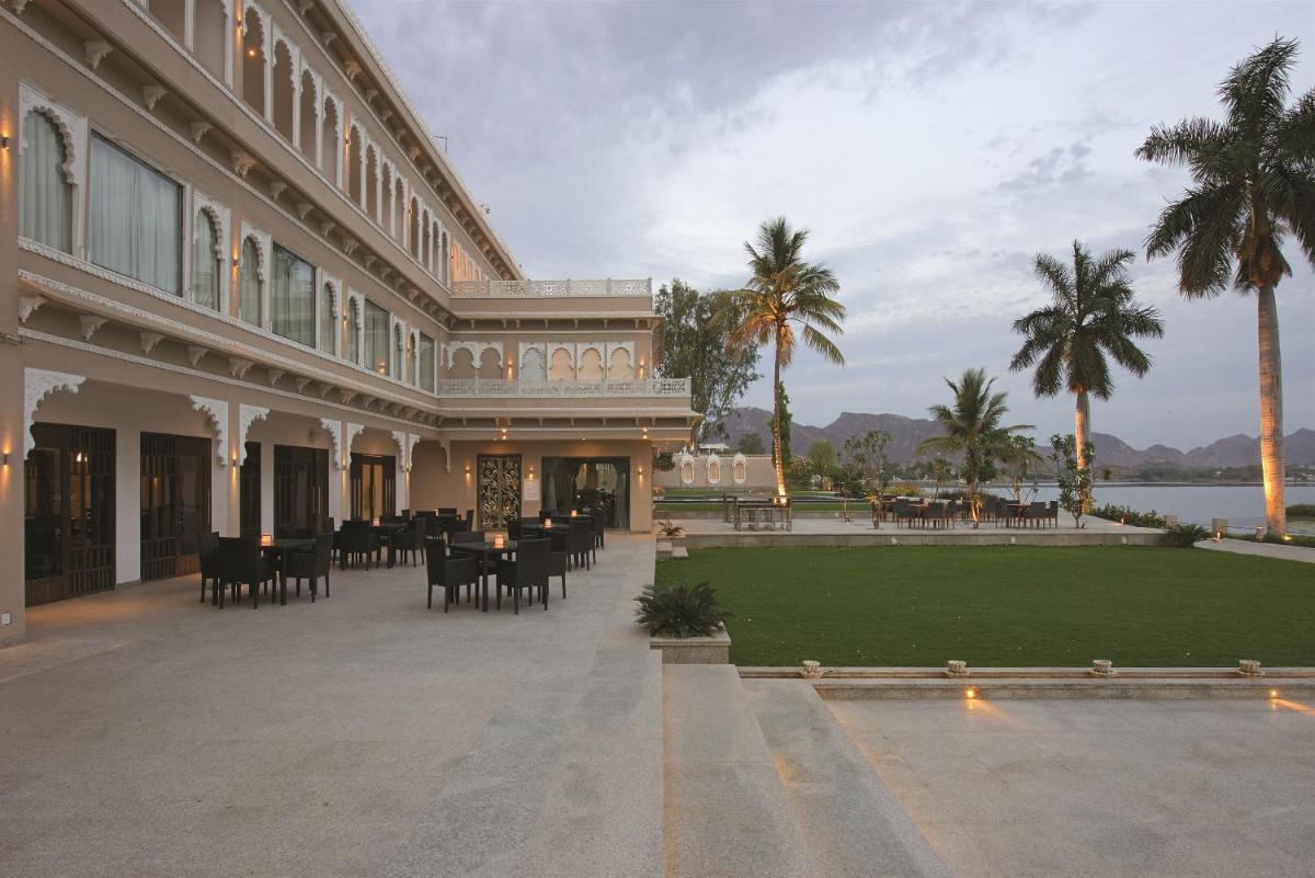 a large building with tables and chairs in a courtyard at Hotel Lakend in Udaipur