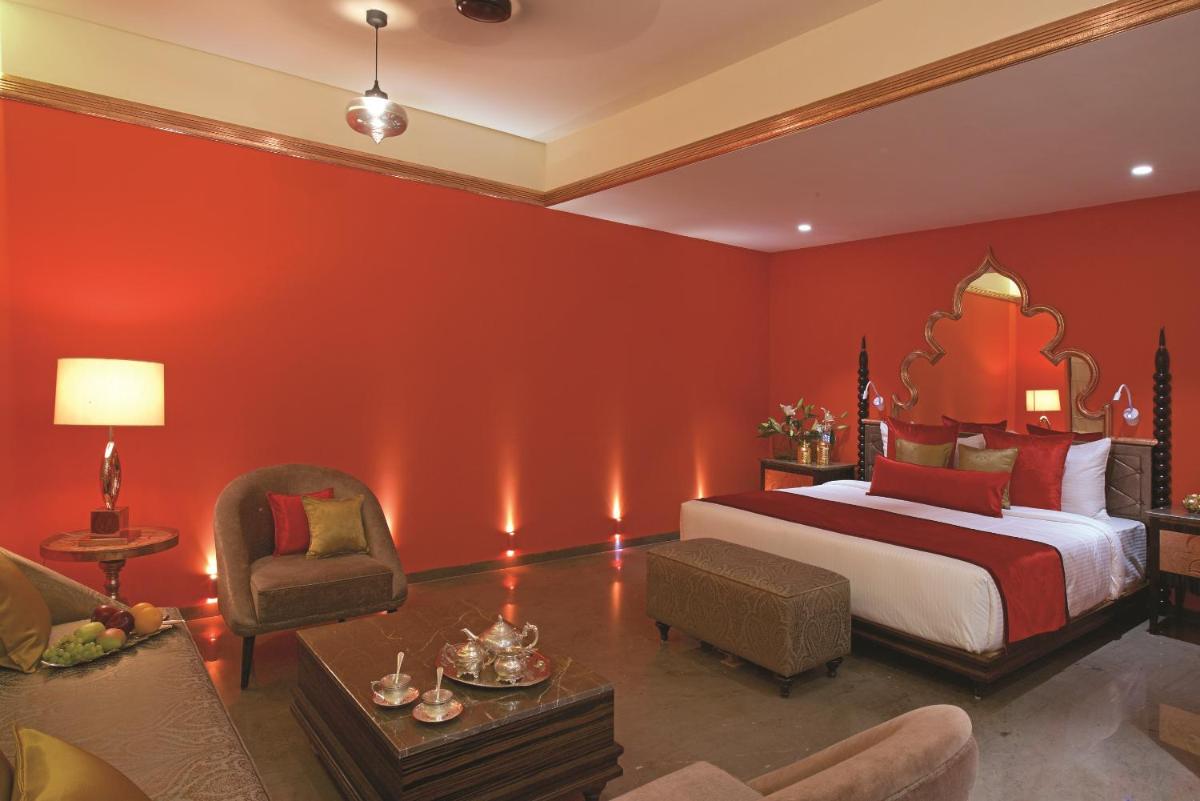 a bedroom with red walls and a bed and a chair at Hotel Lakend in Udaipur