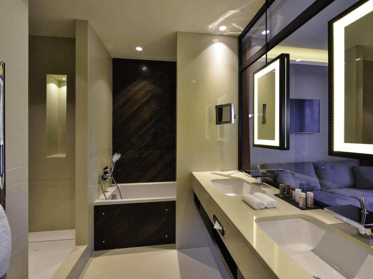 une salle de bain avec deux lavabos et un canapé violet dans l'établissement Grand Hôtel La Cloche Dijon - MGallery Collection, à Dijon