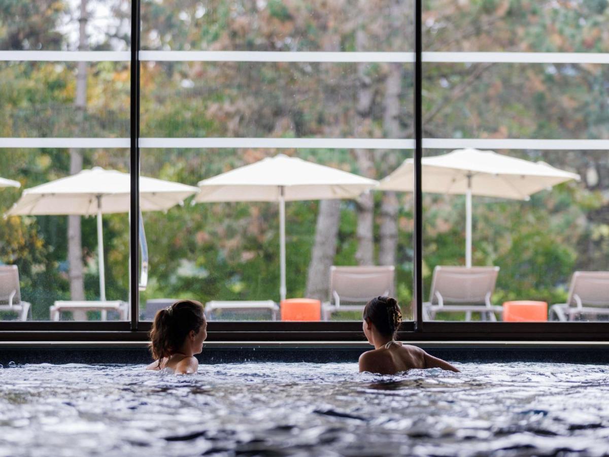 deux filles dans une piscine avec des chaises et des parasols dans l'établissement ibis Styles Aix les Bains Domaine de Marlioz, à Aix-les-Bains