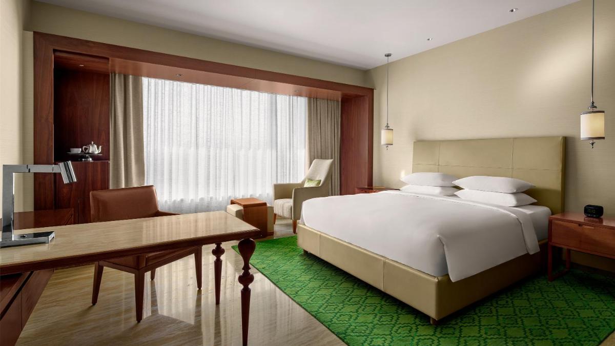 a bedroom with a large white bed and a desk at Park Hyatt Chennai in Chennai