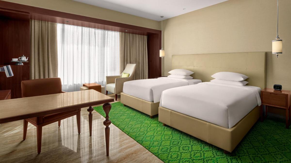 a hotel room with two beds and a desk at Park Hyatt Chennai in Chennai