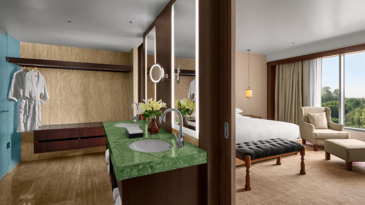 a hotel room with a bed and a bathroom with a sink at Park Hyatt Chennai in Chennai
