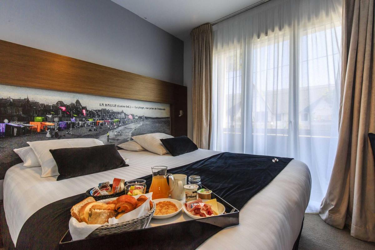 une chambre d'hôtel avec un plateau de nourriture sur un lit dans l'établissement Best Western Hôtel Garden and Spa, à La Baule