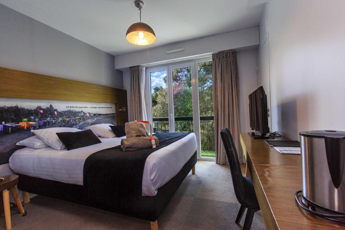 une chambre avec un lit, un bureau et une télévision dans l'établissement Best Western Hôtel Garden and Spa, à La Baule