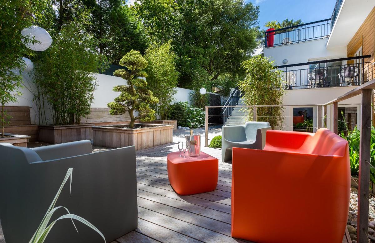 une terrasse avec des chaises et des tables et un bâtiment dans l'établissement Best Western Hôtel Garden and Spa, à La Baule