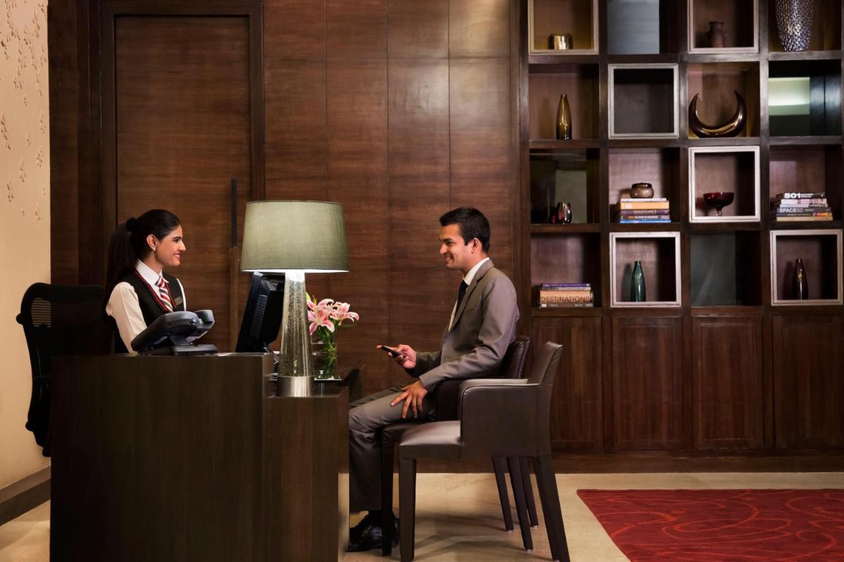 a man and a woman sitting at a reception desk at Bengaluru Marriott Hotel Whitefield in Bengaluru