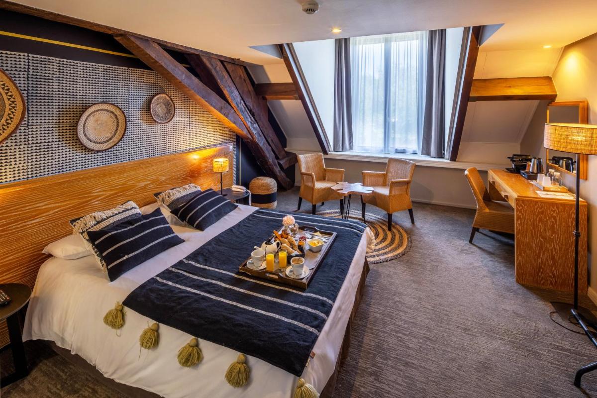 une chambre d'hôtel avec un grand lit et un plateau-repas dessus dans l'établissement Garrigae Manoir de Beauvoir Poitiers Sud - Hotel & Spa, à Mignaloux-Beauvoir