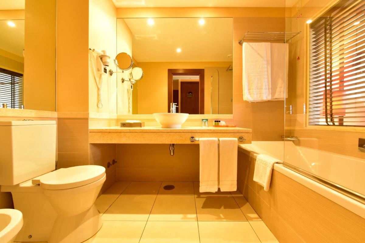 um banheiro com vaso sanitário, pia e banheira em Pestana Porto Santo Premium All Inclusive Beach & SPA Resort em Porto Santo