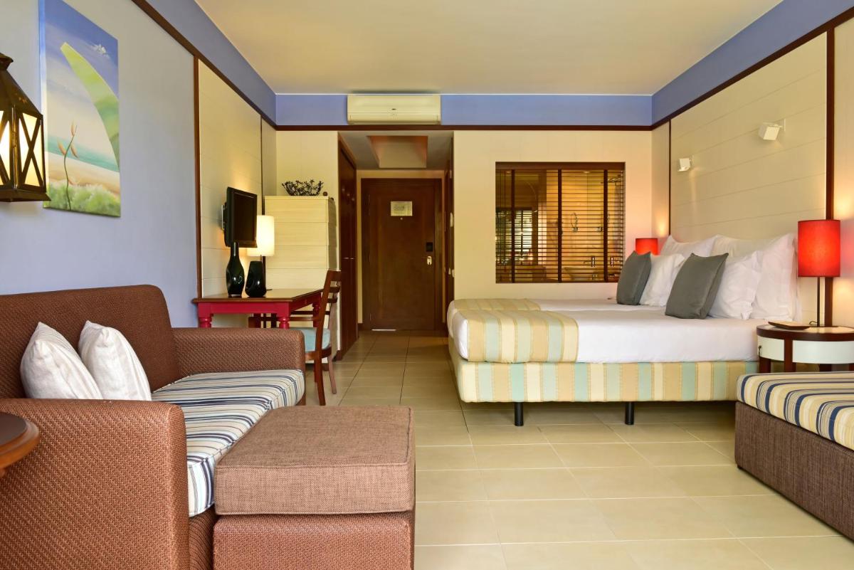 um quarto de hotel com duas camas e um sofá em Pestana Porto Santo Premium All Inclusive Beach & SPA Resort em Porto Santo
