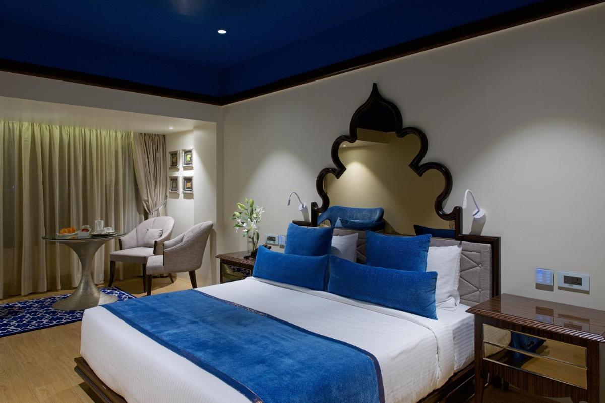a bedroom with a large bed with blue pillows at Hotel Lakend in Udaipur