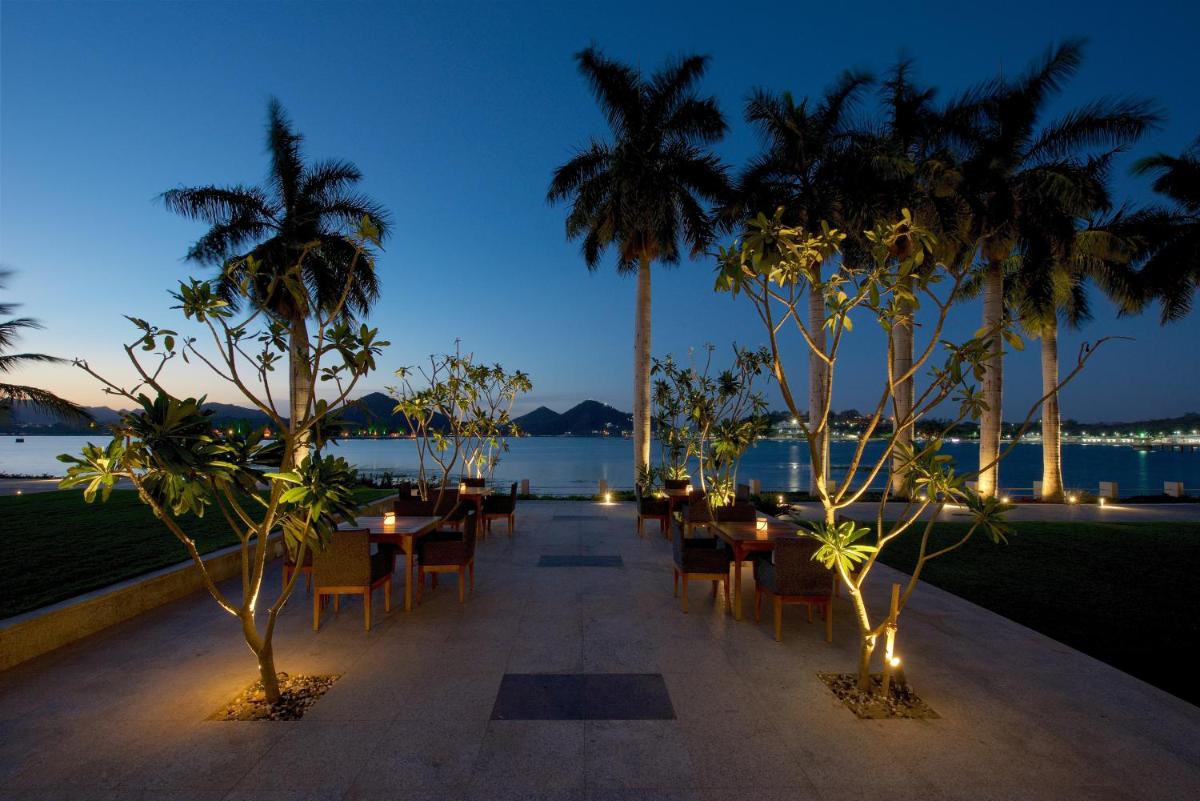 a patio with tables and chairs and palm trees at night at Hotel Lakend in Udaipur