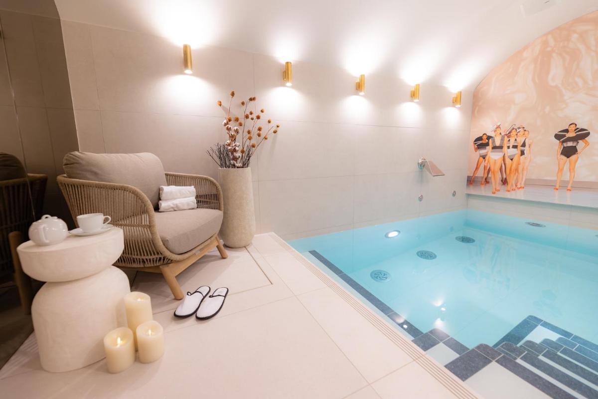 une salle de bain avec piscine équipée d'une chaise et d'un canapé dans l'établissement Hôtel Dress Code, à Paris