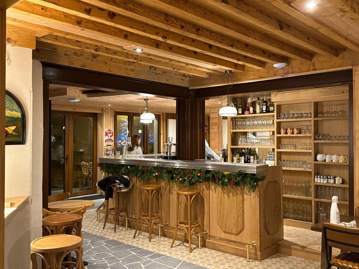 un bar dans un restaurant avec des plafonds et des chaises en bois dans l'établissement Café-Hôtel Le Morillon, Domaine du Grand Massif-Samoëns, à Morillon