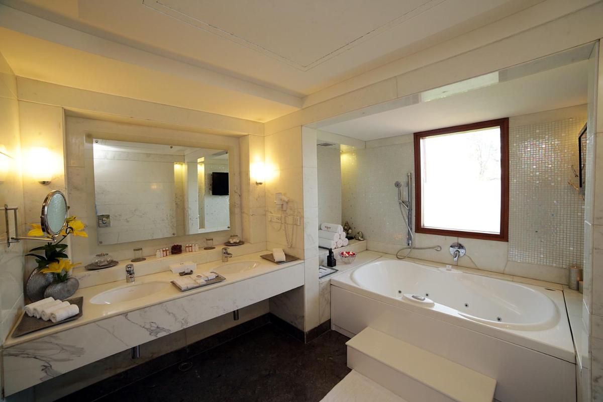 a bathroom with a large tub and a large mirror at Jaypee Palace Hotel in Agra