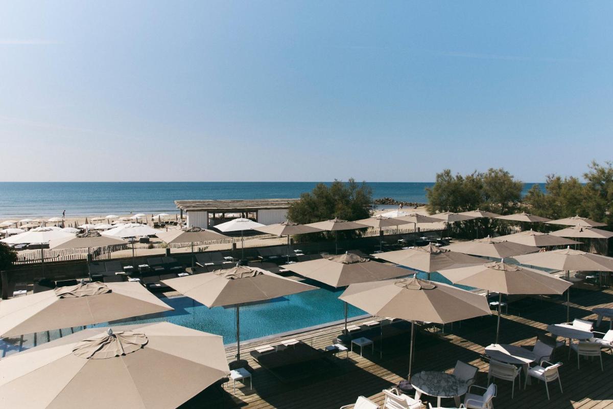 une vue aérienne d'une piscine avec parasols et de l'océan dans l'établissement Hôtel Plage Palace & Spa, à Palavas-les-Flots