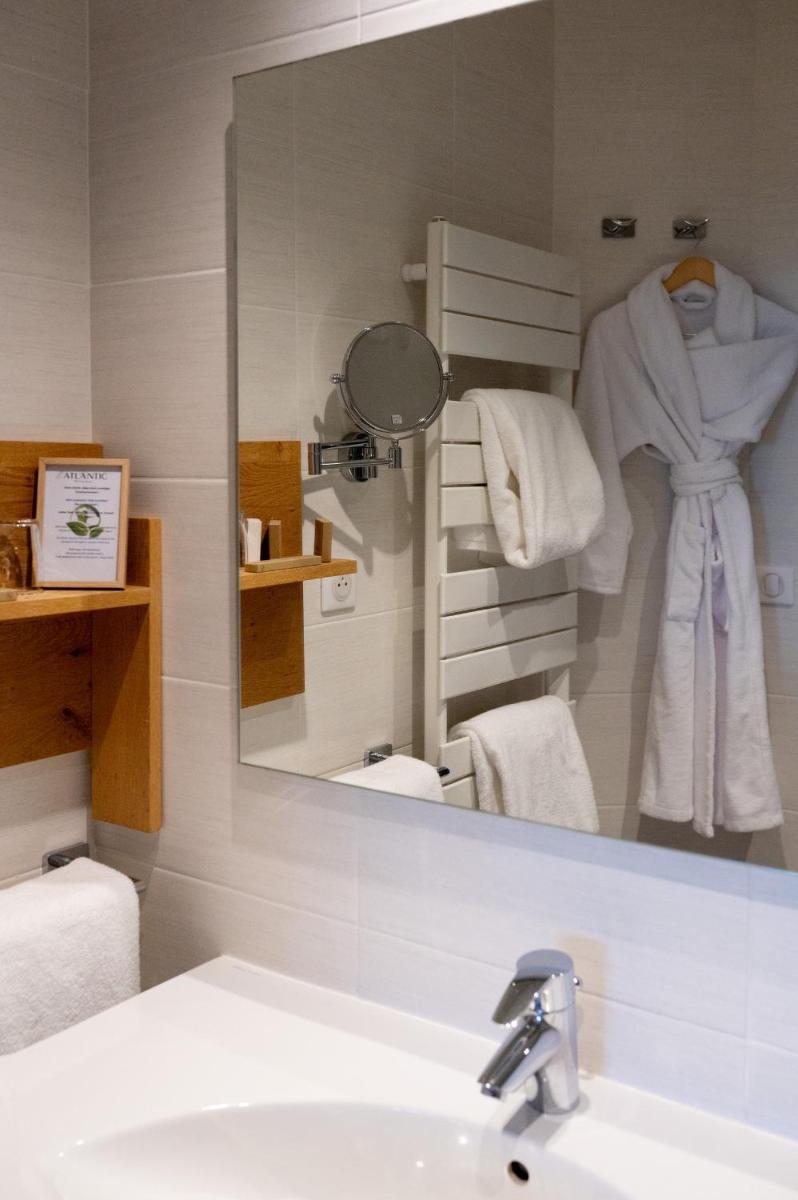 un miroir au-dessus d'un lavabo dans une salle de bain dans l'établissement Hotel Atlantic, à Wimereux 45 autres photos