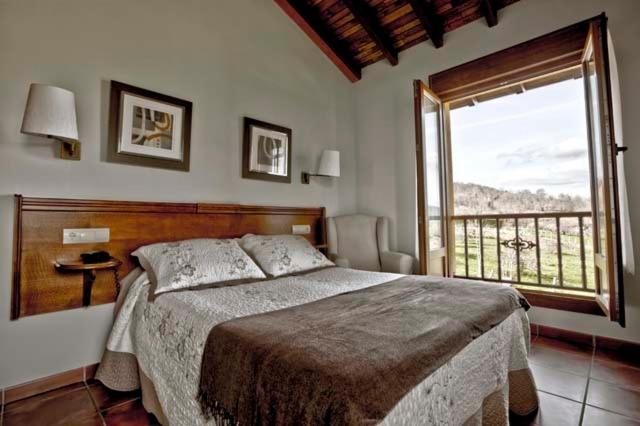 Un dormitorio con una cama grande y una ventana grande. en Hotel & Spa Villa de Mestas, en Cangas de Onís