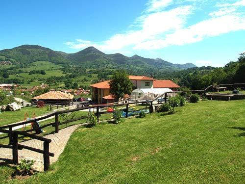 un campo de césped verde con una valla y montañas en Hotel & Spa Villa de Mestas, en Cangas de Onís
