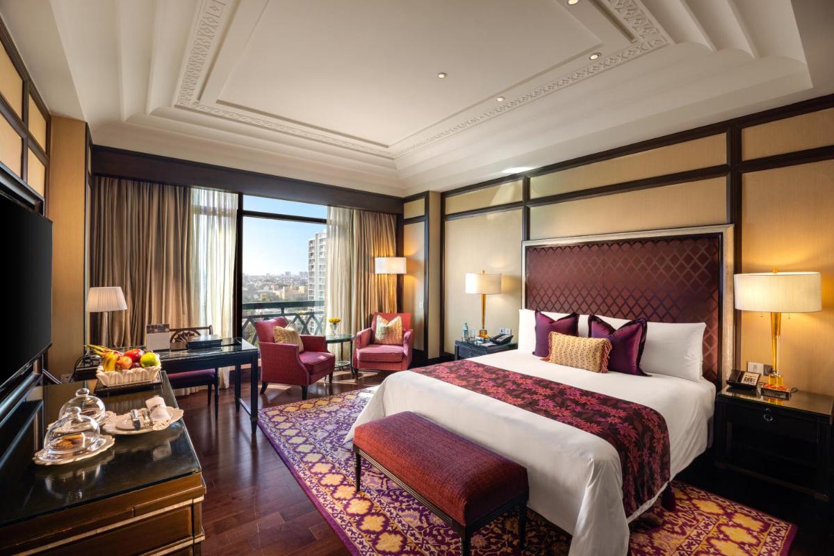 Una habitación de hotel con una cama grande y un escritorio. en The Leela Palace Chennai, en Chennai 90 fotos más