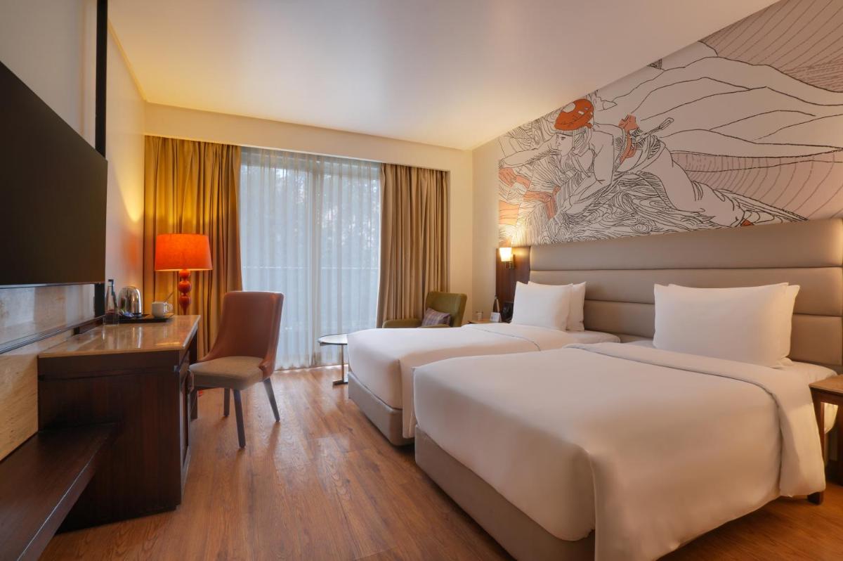 a hotel room with two beds and a television at Hyatt Centric Rajpur Road Dehradun in Dehradun
