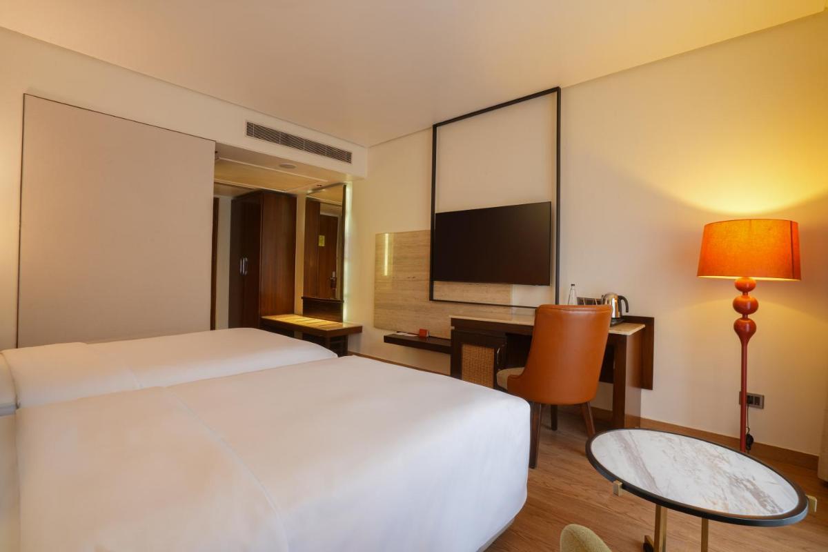 a hotel room with a bed and a desk and a tv at Hyatt Centric Rajpur Road Dehradun in Dehradun