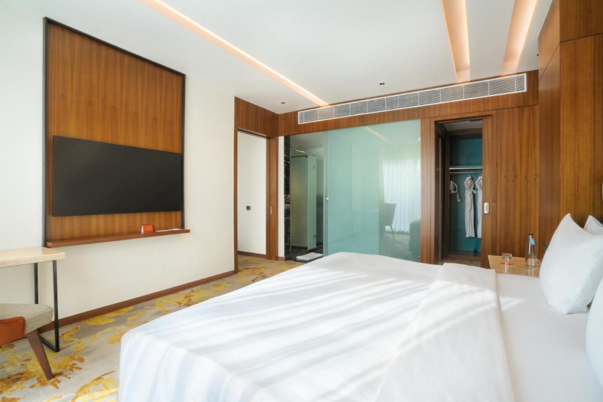 a bedroom with a large bed with a flat screen tv at Hyatt Centric Rajpur Road Dehradun in Dehradun