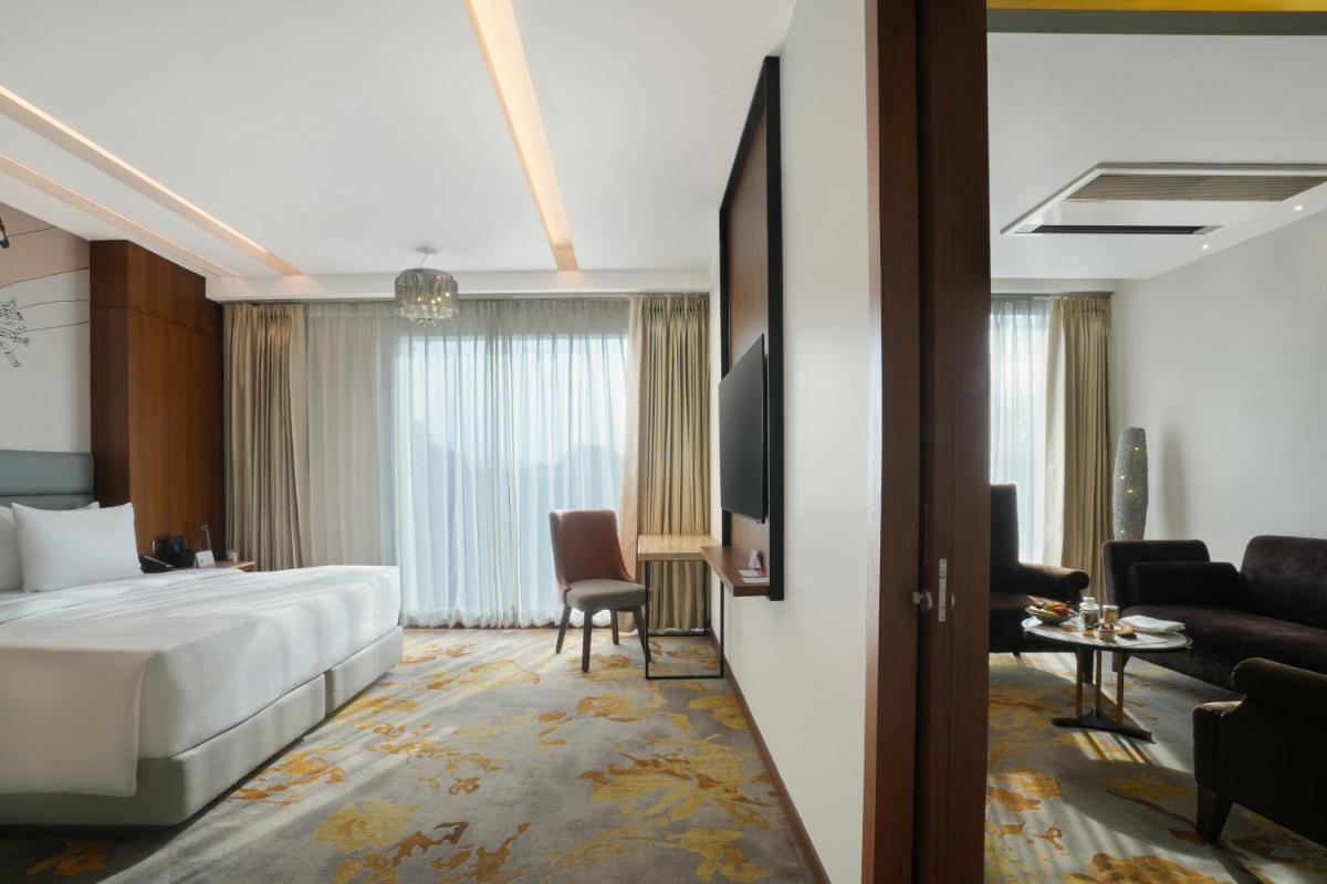 a hotel room with a bed and a living room at Hyatt Centric Rajpur Road Dehradun in Dehradun