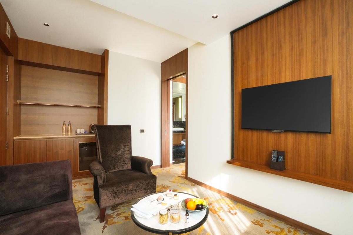 a living room with a tv and a chair and a table at Hyatt Centric Rajpur Road Dehradun in Dehradun