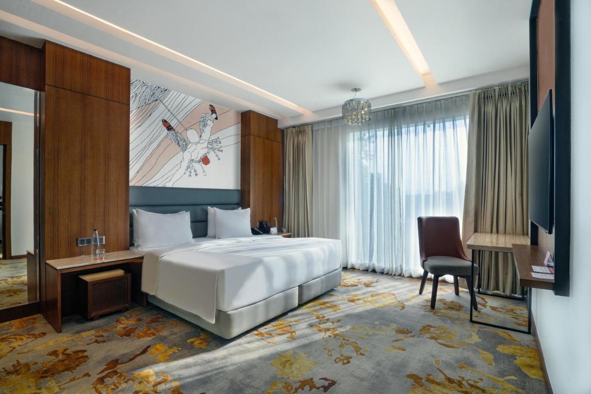 a bedroom with a bed and a desk and a chair at Hyatt Centric Rajpur Road Dehradun in Dehradun